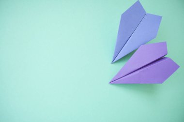 Düz metin alanı ile iki mor kağıt uçakların pastel pembe ve mavi zemin üzerinde yatıyordu.