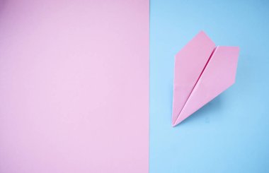 Düz metin alanı ile mor kağıt uçak pastel pembe ve mavi zemin üzerinde yatıyordu.