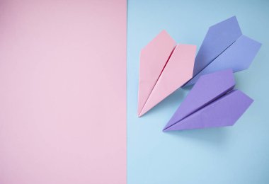 Düz metin alanı ile üç kağıt uçakların pastel pembe ve mavi zemin üzerinde yatıyordu.
