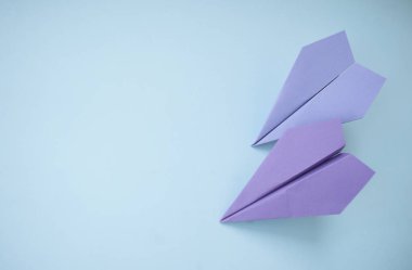 Düz metin alanı ile iki mor kağıt uçakların pastel mavi zemin üzerinde yatıyordu.