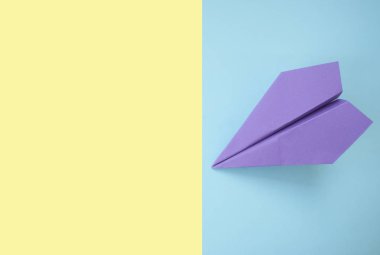 Düz metin alanı ile kağıt uçak parlak sarı ve mor zemin üzerinde yatıyordu.