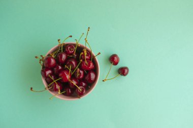 Bir kase kiraz, metin için yer ile turkuaz arka plan üzerinde ile.