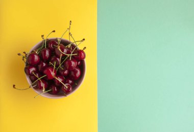 Bir kase kiraz turkuaz ve sarı zemin üzerine ile.