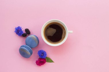 Bir fincan siyah taze kahve, kurabiye ve metin alanı pastel pembe zemin üzerine güzel çiçekler.