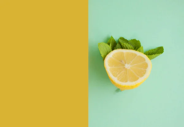 Top view of lemons and mint on yellow and turquoise background with space for your text.