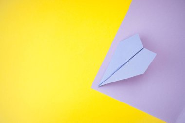 Düz metin alanı ile kağıt uçak parlak sarı ve mor zemin üzerinde yatıyordu.