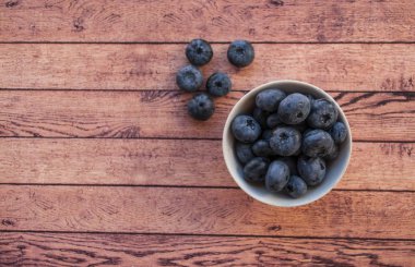 Taze ve sulu yaban mersini boşaltmak ile ahşap masa üzerinde beyaz bir kase. Sağlıklı gıda kavramı.