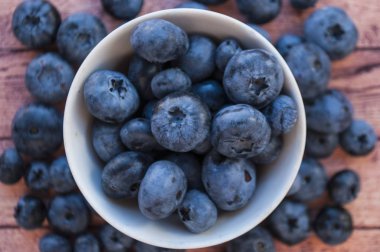 Bir taze ahşap masa üzerinde beyaz bir kapta sulu yaban mersini aldı kapatın. Sağlıklı gıda kavramı.