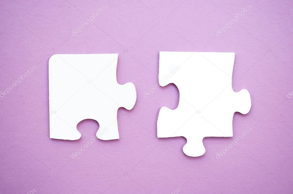 Two puzzle pieces on pink background as a symbol of autism awareness.