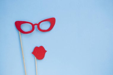 Kırmızı parlak fotoğraf booth sahne gözlük ve mavi arka plan ile boşaltmak dudaklarından.