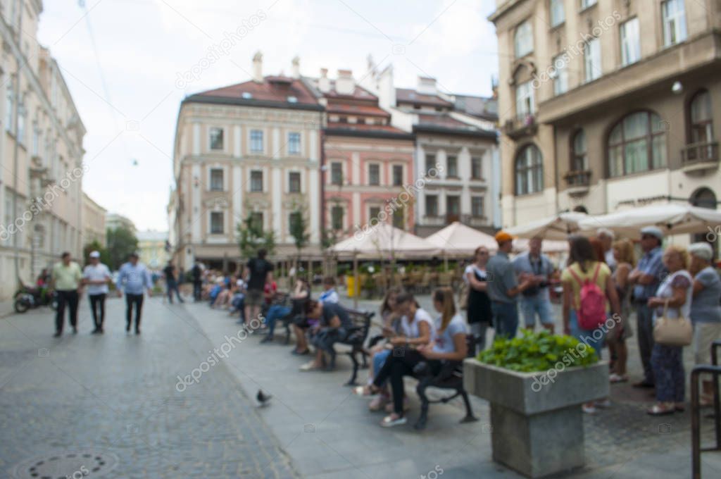 Blurred view of an old european square filled with people in a small magical town. Evening time promenade.