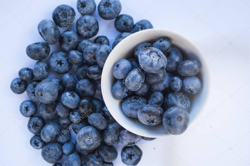 Fresh blueberries in a white bowl on white table.