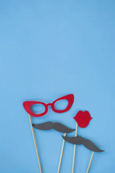 Colorful photo booth props glasses, lips, moustache and on blue background with copyspace. Set of party props.