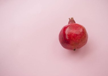 Flat lay of ripe red pomegranate fruit on a pink background with copyspace. Healthy food concept. clipart