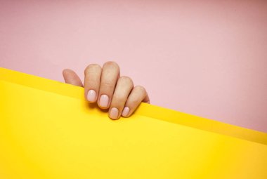 Güzel genç kadının el pembe ve sarı zemin üzerine.