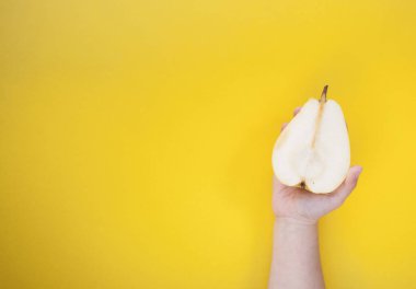 İki tatlı ve olgun armut hchild'ın elindeki sarı bir arka plan üzerinde sarı. Çok az yiyecek konsepti.