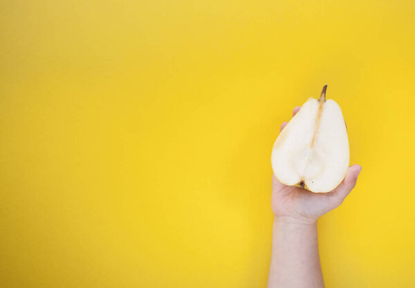 Две желтые сладкие и спелые груши в руке ребенка на желтом фоне. Минимальная концепция питания
.