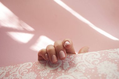 Young woman's hand with beautiful manicure on pastel pink background with copyspace. clipart