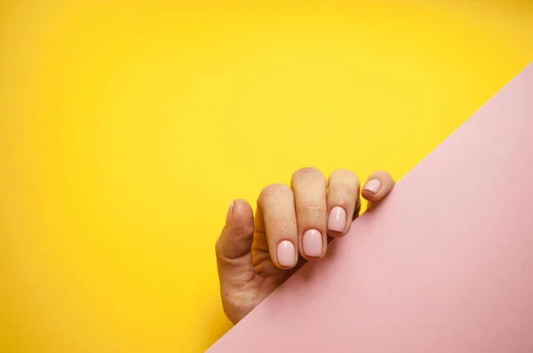 Hermosa mano de las mujeres jóvenes sobre fondo rosa y amarillo . — Foto de Stock