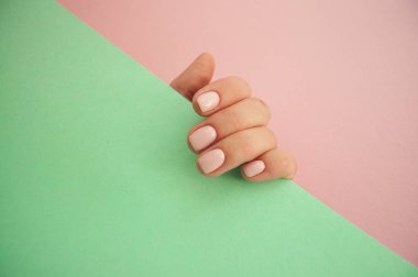 Genç kadının el ile boşaltmak pembe ve turkuaz zemin üzerine güzel manikür.