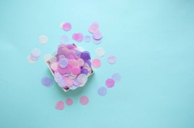 Düz kutu pastel mavi ve pembe arka plan üzerinde renkli konfeti boşaltmak ile dolu, lay.