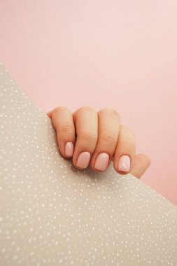 Genç kadının el ile boşaltmak ile pembe ve bej renkli arka plan üzerinde güzel manikür.