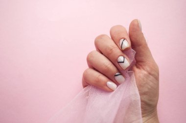 Genç kadının el ile tül ile boşaltmak bir parçası tutan pembe arka plan üzerinde güzel manikür.