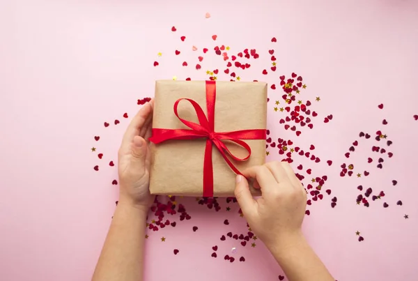 Caixa de presente amarrada com fita vermelha no fundo rosa pastel . — Fotografia de Stock