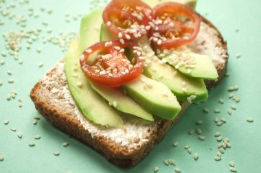 Lezzetli tost dilimlenmiş avokado, domates ve sesamum tohumlar üzerinde boşaltmak ile mavi arka plan ile. Sağlıklı gıda kavramı.