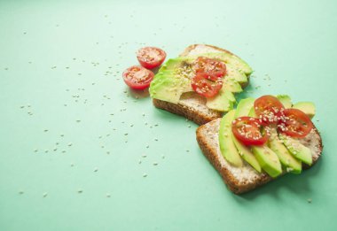 Düz lezzetli tost dilimlenmiş avokado, domates ve sesamum tohum boşaltmak mavi zemin üzerine yatırın. Sağlıklı gıda kavramı.
