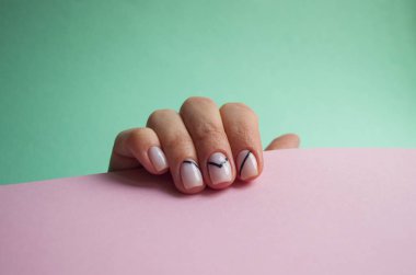 Genç kadının el ile boşaltmak ile mavi ve pembe arka plan üzerinde güzel manikür.