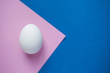 Boşaltmak koyu mavi ve pastel pembe zemin üzerine beyaz bir tek yumurta.