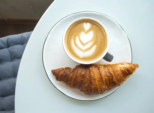 Croissant mit Marmelade, Butter und einer Tasse Kaffee. — Stockfoto