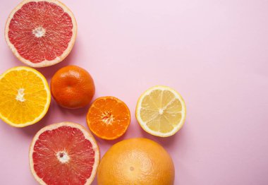 Düz kesim olgun sulu greyfurt, limon, portakal ve mandalina boşaltmak ile pembe arka plan üzerinde yatıyordu. Narenciye desen.