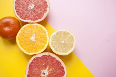 Düz kesim olgun sulu greyfurt, limon ve portakal pembe ve Sarı zemin üzerine yatıyordu. Narenciye desen.