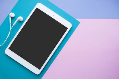 Tablet ve parlak renkli arka plan üzerinde kulaklık.