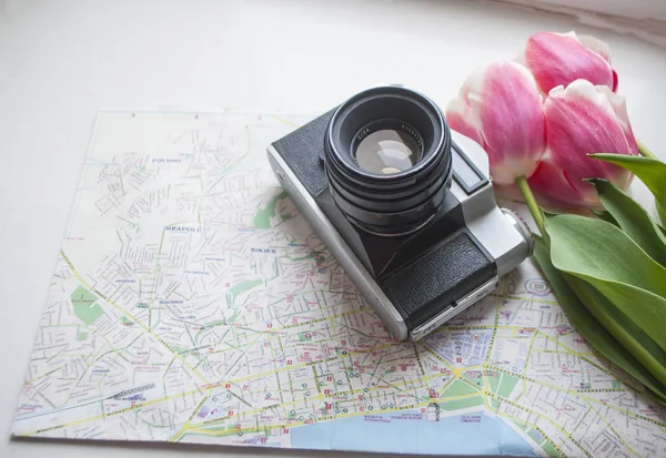 Flat lay of map, camera and tulips boquet. Travel concept.