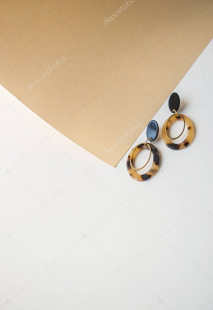 Earrings on beige and brown color background.