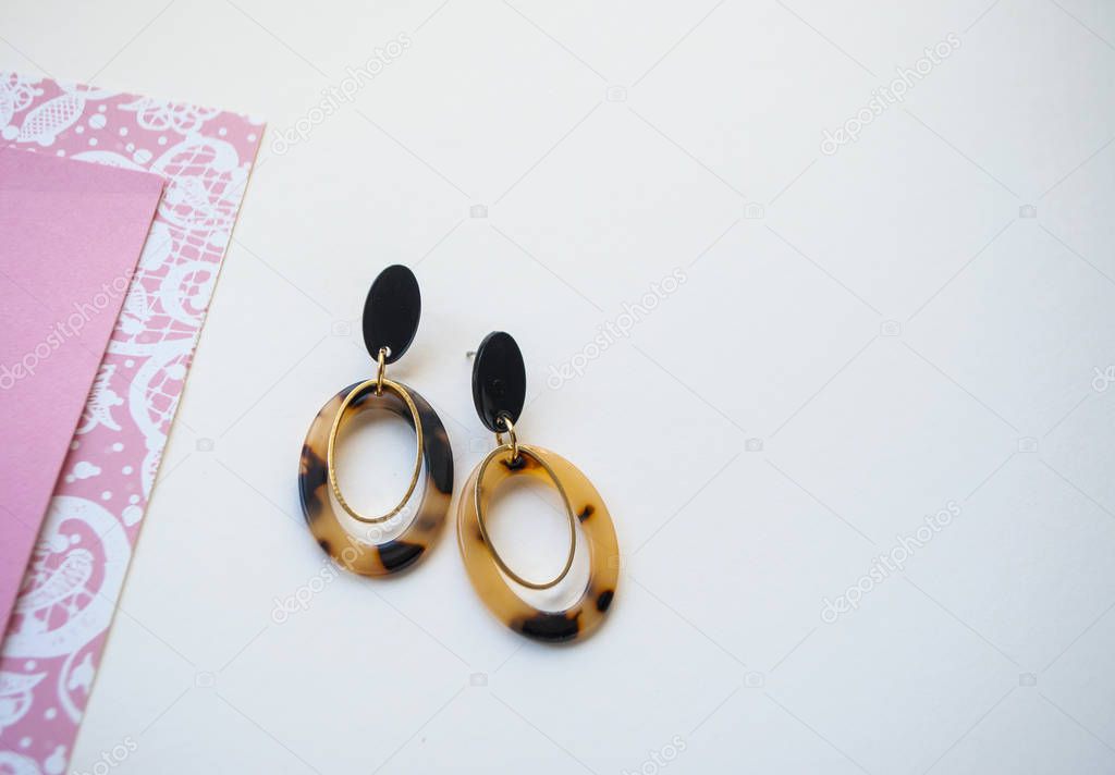 Earrings on beige and brown color background.