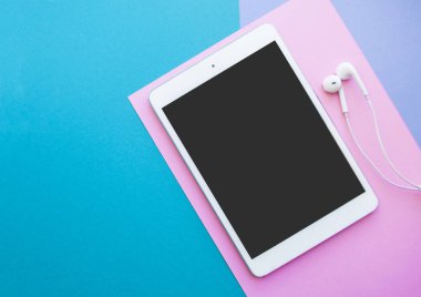 Tablet ve parlak renkli arka plan üzerinde kulaklık.