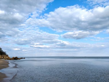 Bulutlu gökyüzü ve denizin geniş ufkuyla rahatlatıcı deniz manzarası..