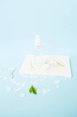 El antiseptiği sprey şişesinde ve güzel açan kiraz ağacı çiçekleri ve mavi arka planda taze yeşil yapraklar. Coronavirüs kavramını durdur.