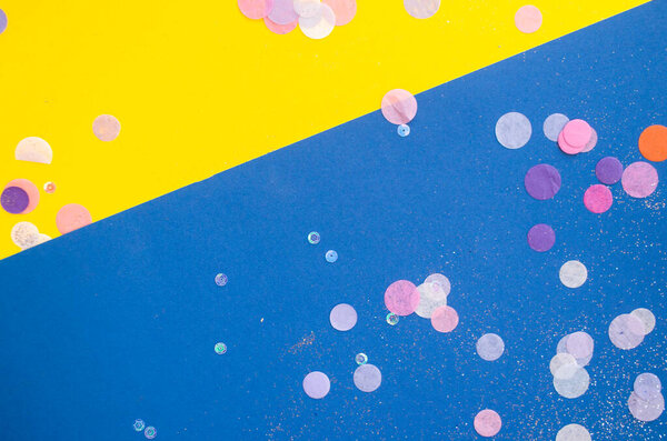 Colorful confetti, sparkles on bright yellow and classic blue background. Festive background.