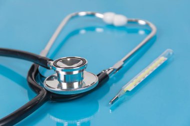Steteskop ve mavi arka plan üzerinde termometre