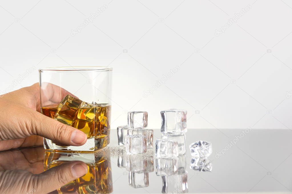 hand holding glass of whiskey with ice cubes