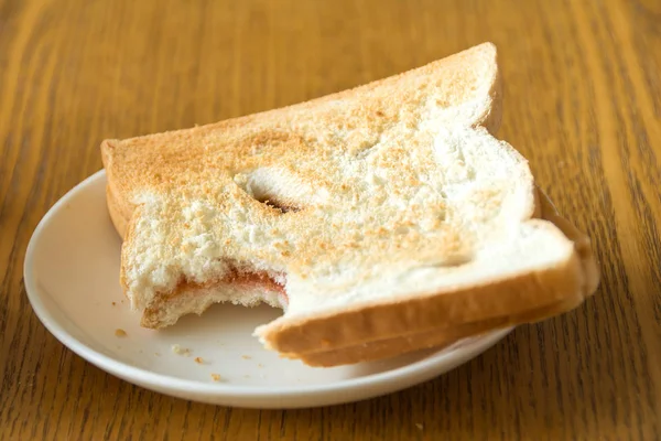 bitten bread in a white plate on wooden table