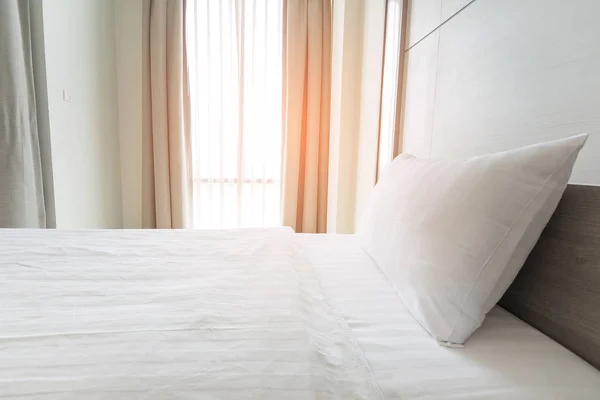white bedding sheets and white pillow in bedroom.sunshine throug