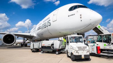BERLIN, GERMANY - APR 27, 2018: Airbus A350 XWB passenger plane about to be towed by airport equipment at the Berlin ILA Air Show. clipart