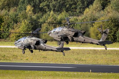 EINDHOVEN, THE NETHERLANDS - OCT 27, 2017: Two US Army Boeing AH-64D Apache attack helicopters leaving Eindhoven airbase. clipart