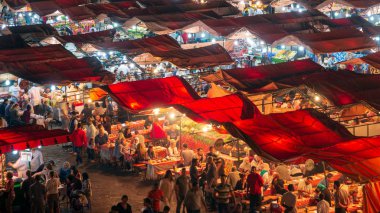 MARRAKECH, MOROCCO - APR 27, 2016: Food stalls at sunset on the Djemaa El Fna square. In the evening the large square fills with food stands, attracting crowds of locals and tourists. clipart
